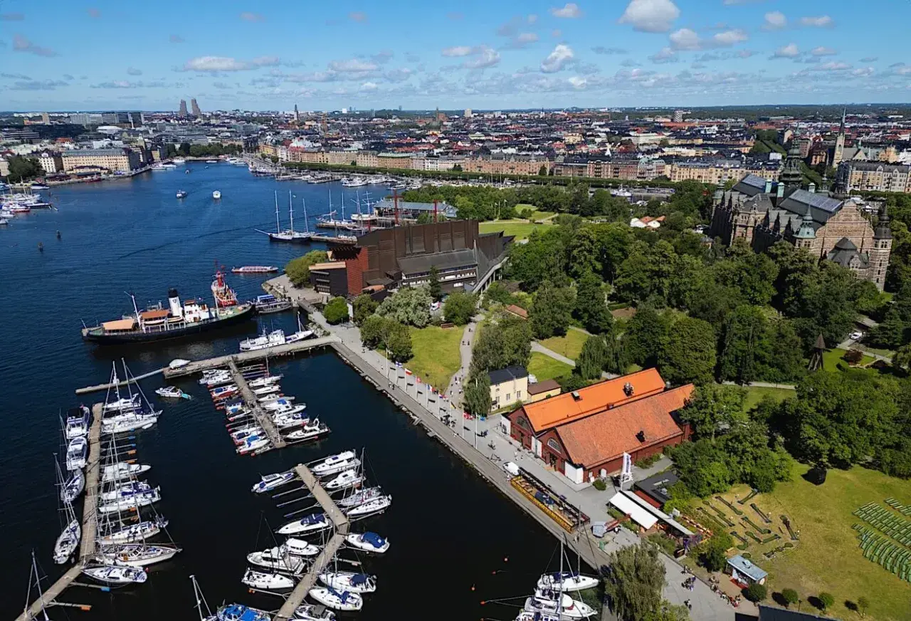 Stockholms hamn med många båtar och en byggnad som liknar Vin & Sprit Museet.