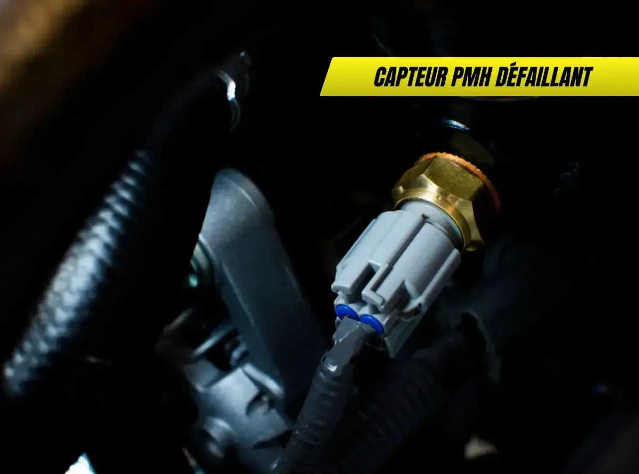 Capteur PMH défaillant : un composant moteur avec un connecteur gris et un corps hexagonal doré, entouré de câbles noirs.