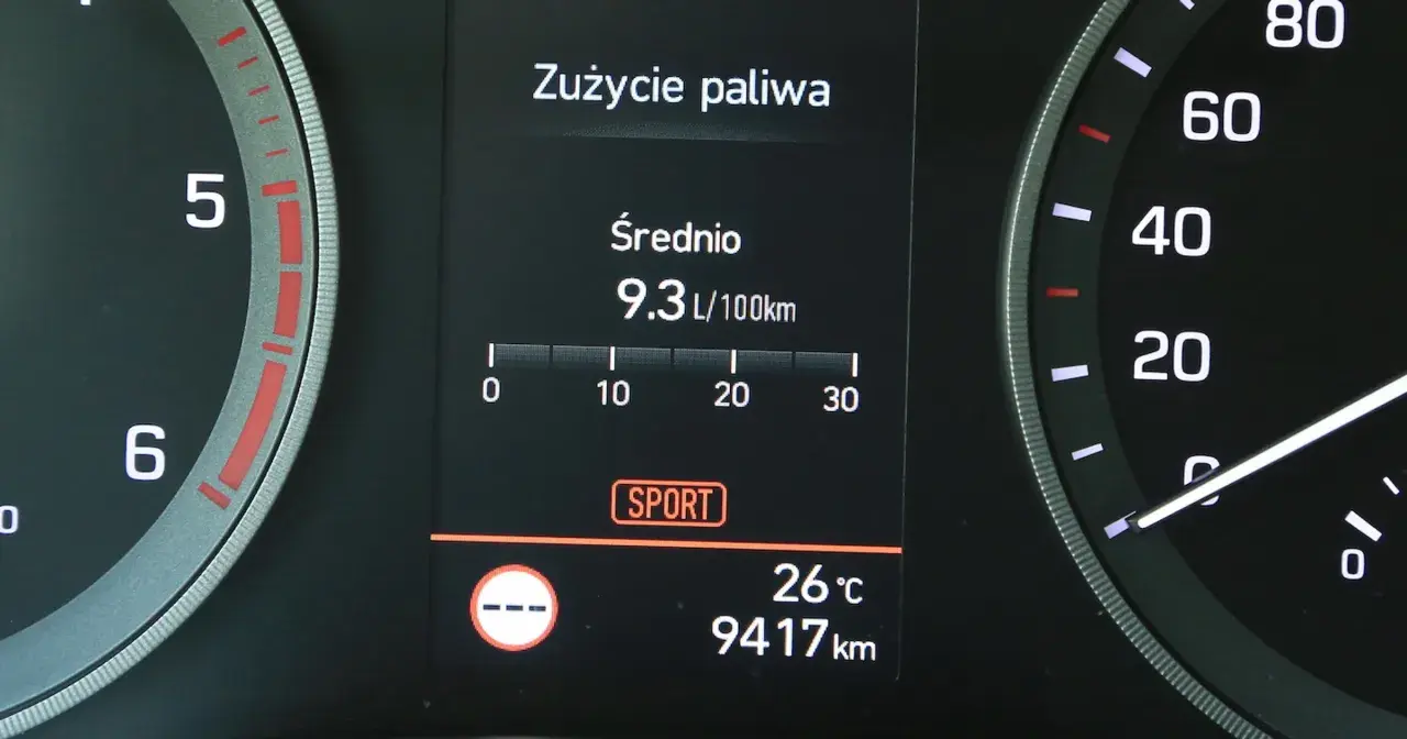 Na wyświetlaczu samochodu widać licznik spalania paliwa: średnie zużycie 9.3 L/100km. Obok widnieje tryb SPORT.