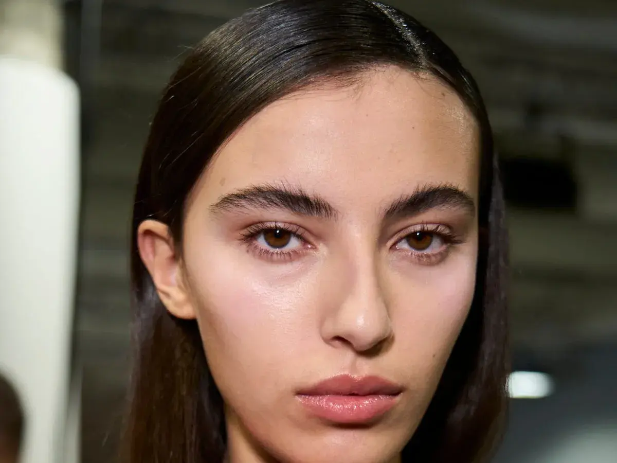 Primer plano de una joven con cejas pobladas y mirada intensa. Su piel luce natural y sus labios están ligeramente brillantes.