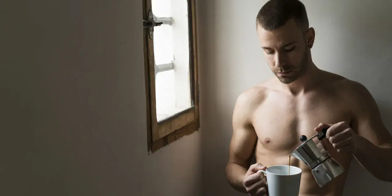 Uomo nudo versa caffè, riflessione sulla psicologia di un uomo sposato. Luce soffusa da una finestra.