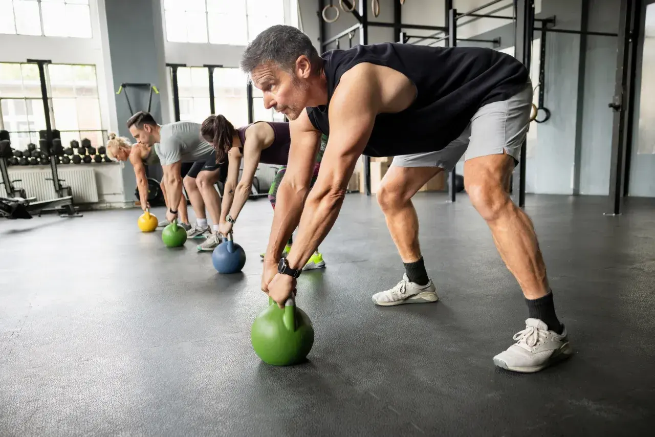 Gruppe trainiert Griffkraft mit Kettlebells. Sie heben die Gewichte vom Boden, um ihre Hände zu stärken.
