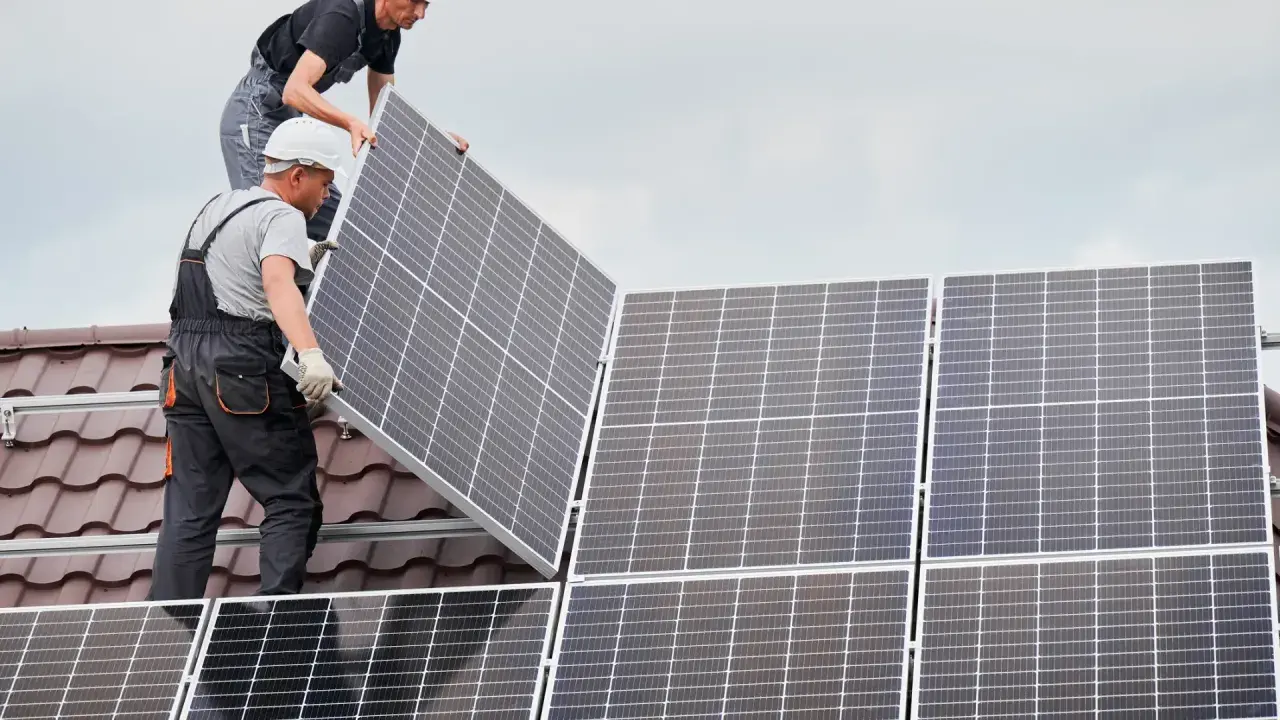 Instaladores colocan placas solares en un tejado, asegurando el anclaje para la energía limpia.