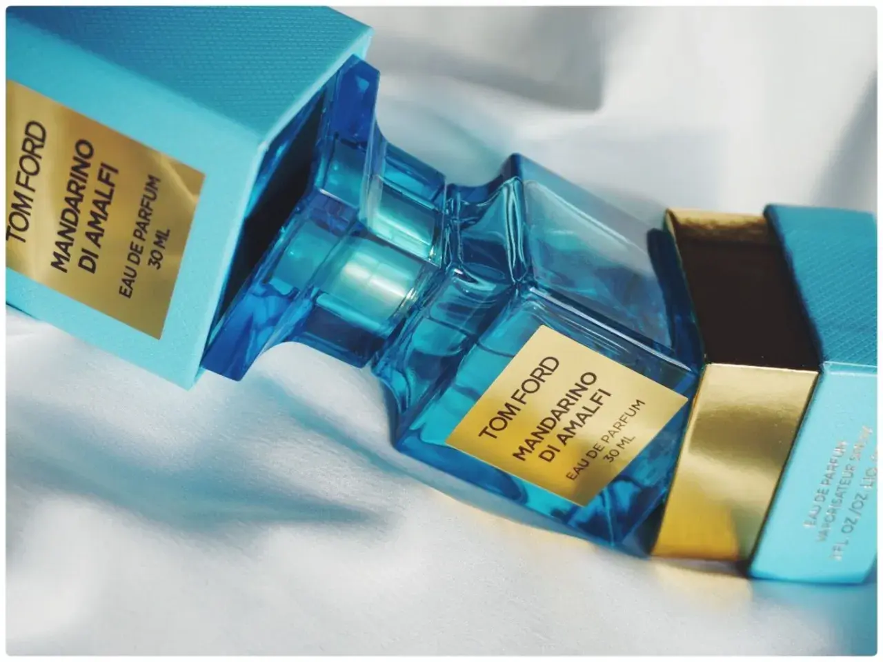 Błękitne pudełko i szklana butelka perfum Tom Ford Mandarino di Amalfi, emanujące świeżością włoskiego wybrzeża.