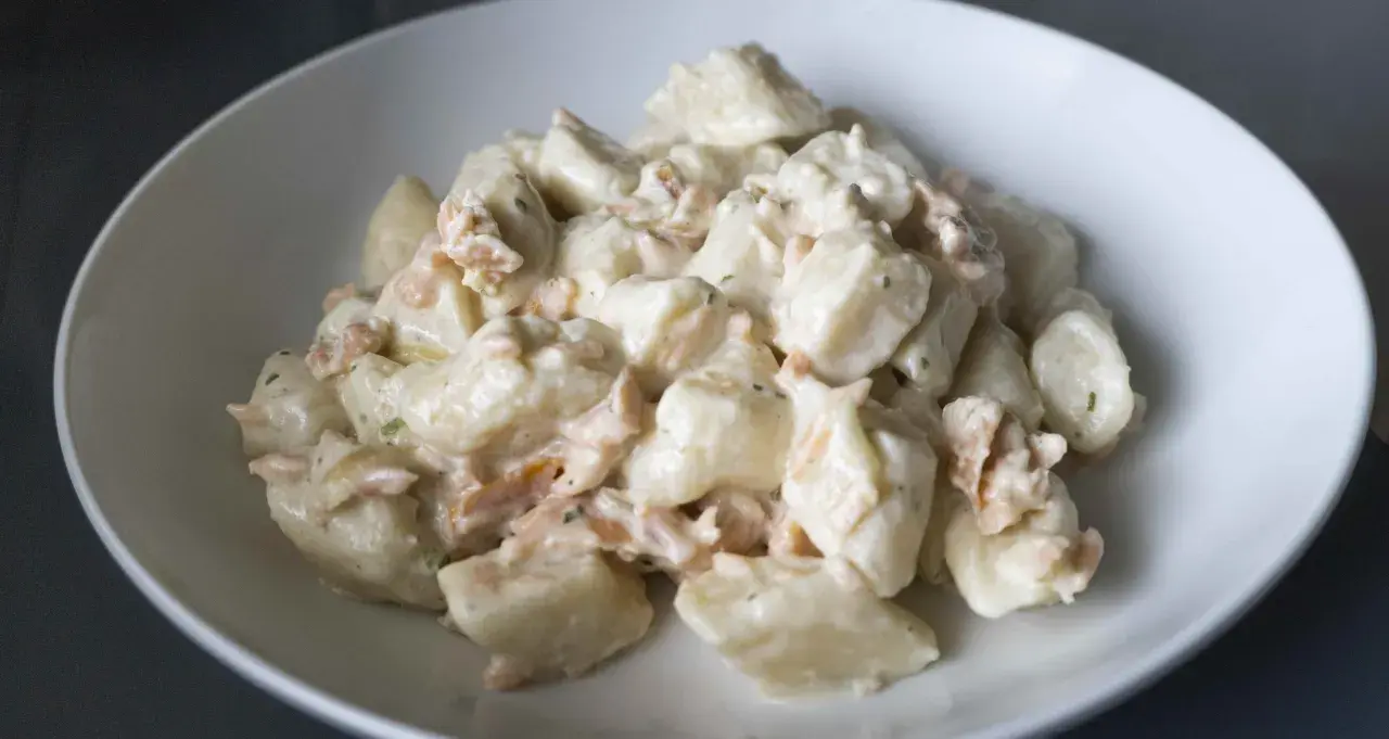 Puszyste gnocchi z ricottą i kawałkami łososia w kremowym sosie, podane w białej misce.