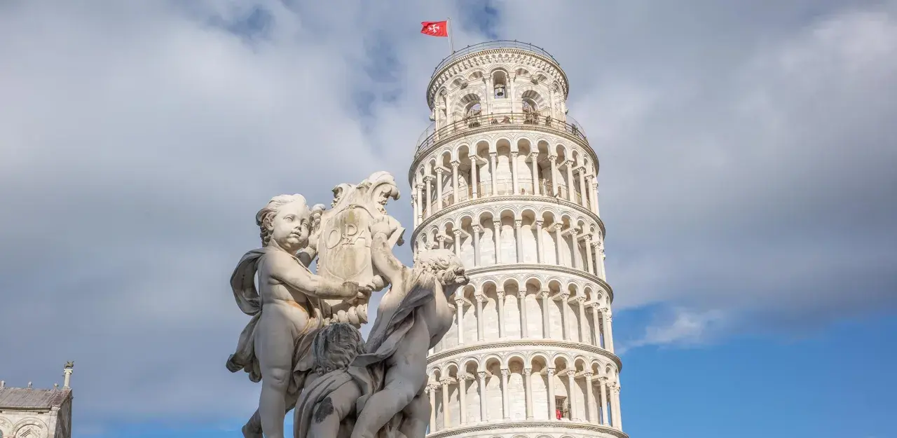 Die Torre de Pisa, ein schiefer Turm, ragt hinter einer barocken Skulptur auf.