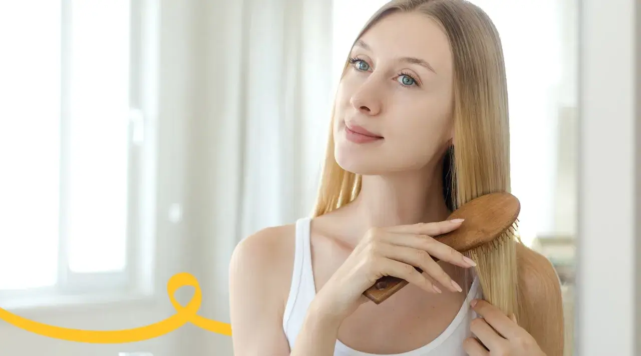 Kobieta szczotkuje włosy, przygotowując domowy peeling do skóry głowy.