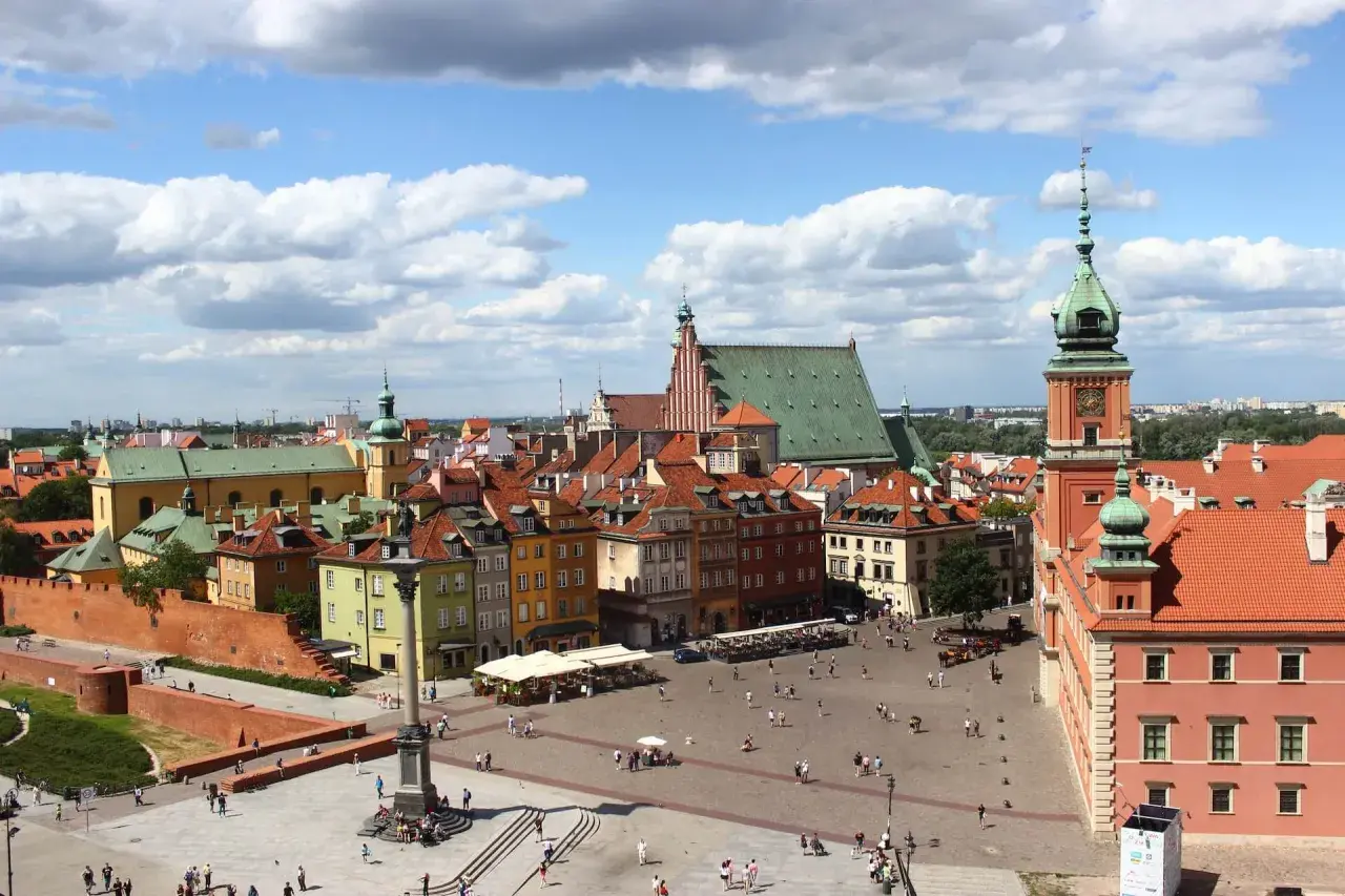 Widok na Zamek Królewski i Rynek Starego Miasta w Warszawie. Kolorowe kamienice, kolumna Zygmunta i tłumy turystów.