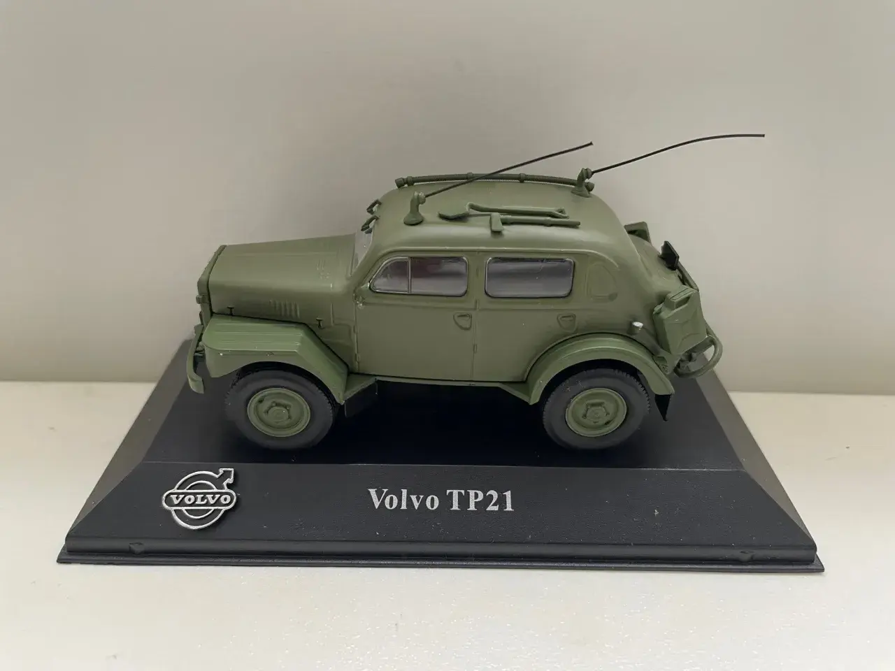Modell av en grön Volvo TP21 "Sugga" med antenner och takräcke, monterad på en svart piedestal.