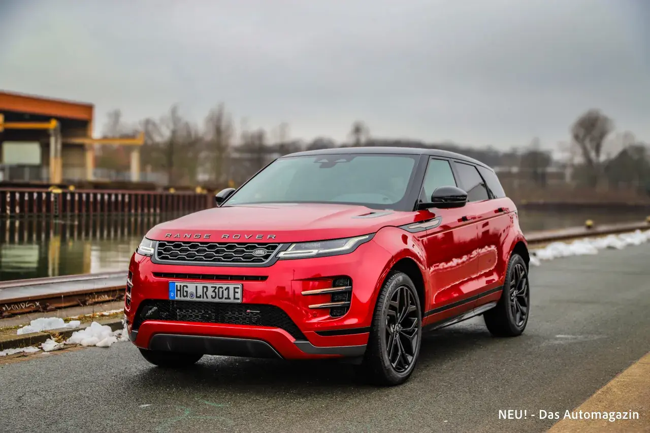 Roter Range Rover Evoque parkt am Wasser. Die Anhängelast ist für Abenteuer bereit.
