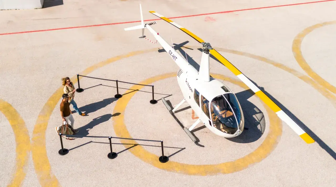 Para zwiedzających zbliża się do helikoptera. Sprawdź hopper ceny biletów na niezapomnianą podróż!