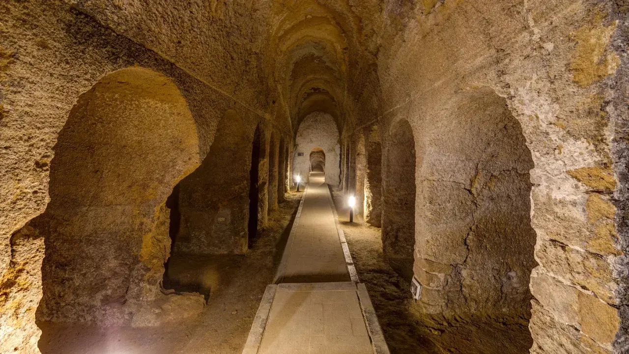 Corridoio sotterraneo scavato nella roccia a Camerano, Ancona, con illuminazione soffusa che crea un'atmosfera suggestiva.