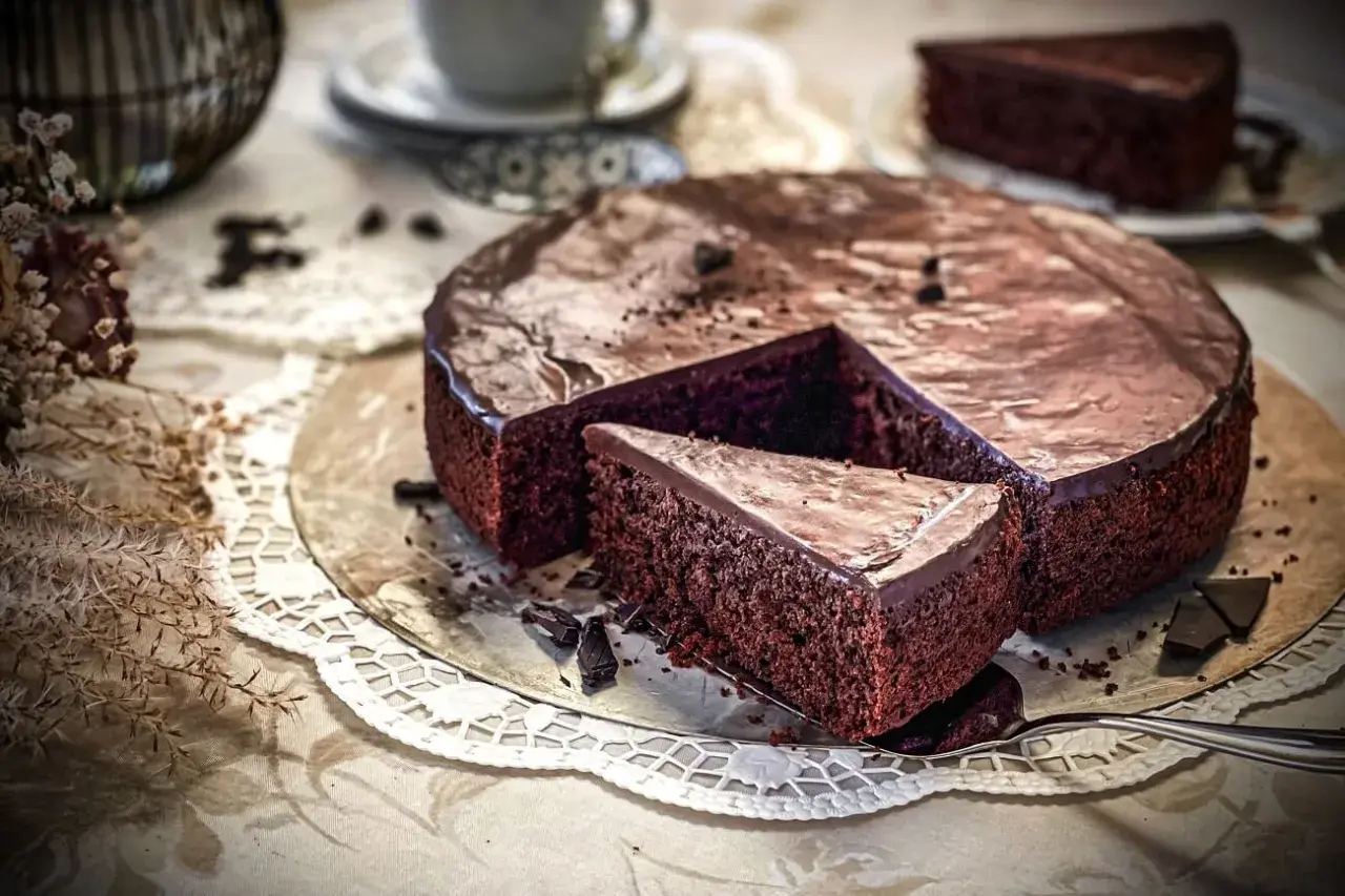 Ein saftiger Schokoladenkuchen mit glänzender Glasur, ein Stück wurde bereits entnommen. Dieses schokoladenkuchen rezept saftig ist ein Traum!