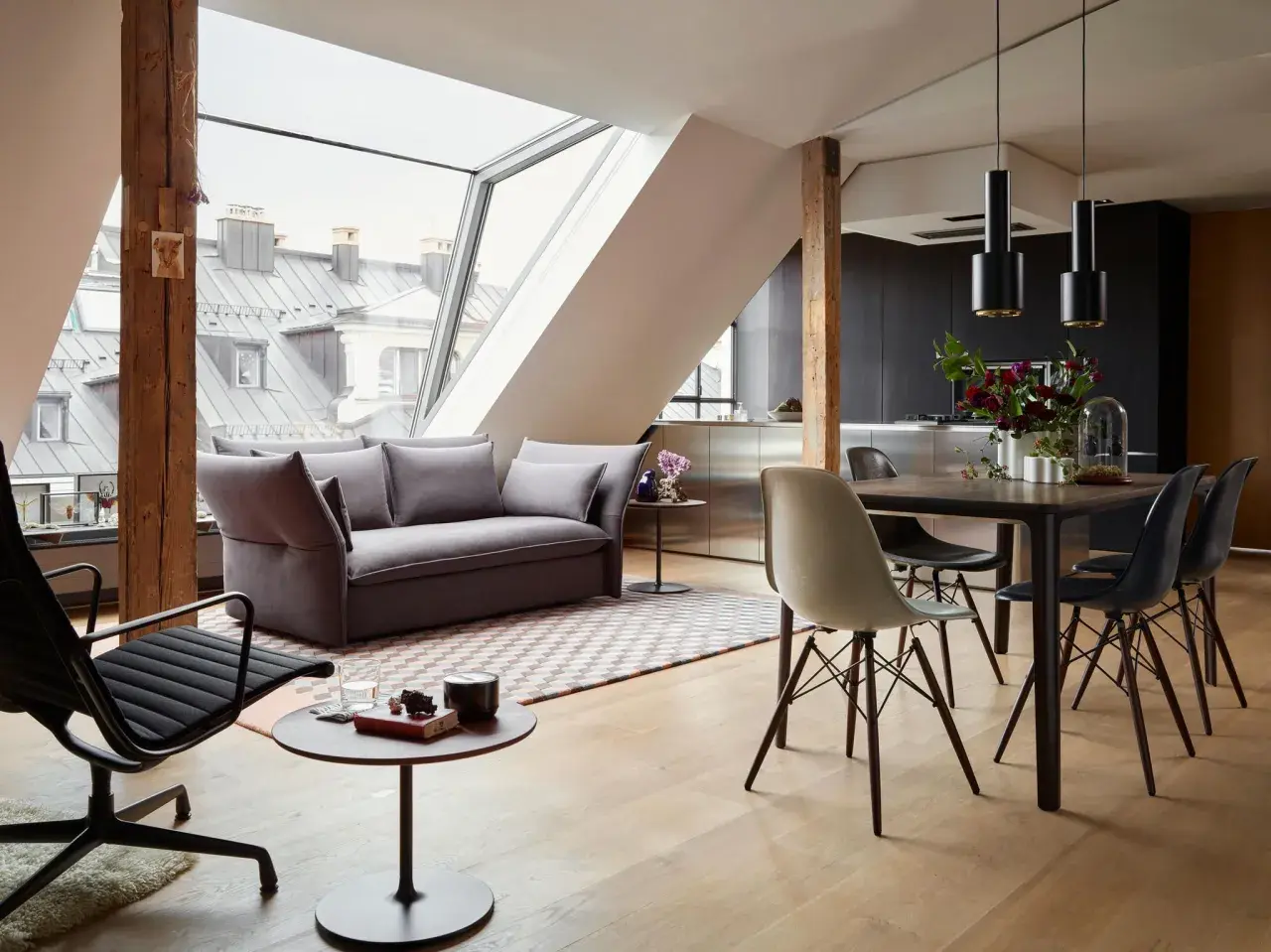 Modernes Wohnzimmer mit Dachfenster: Hier lässt sich Sofa und Esstisch gut kombinieren. Graues Sofa, Holzboden, schwarzer Esstisch mit Stühlen.