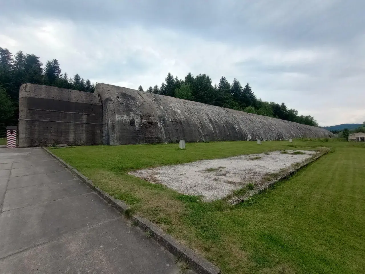 Ogromny betonowy bunkier w Frysztaku, otoczony zielenią i lasem.