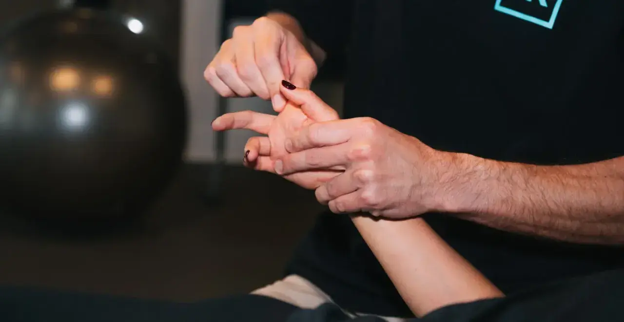 Un thérapeute manipule délicatement un doigt, peut-être pour traiter une luxation.