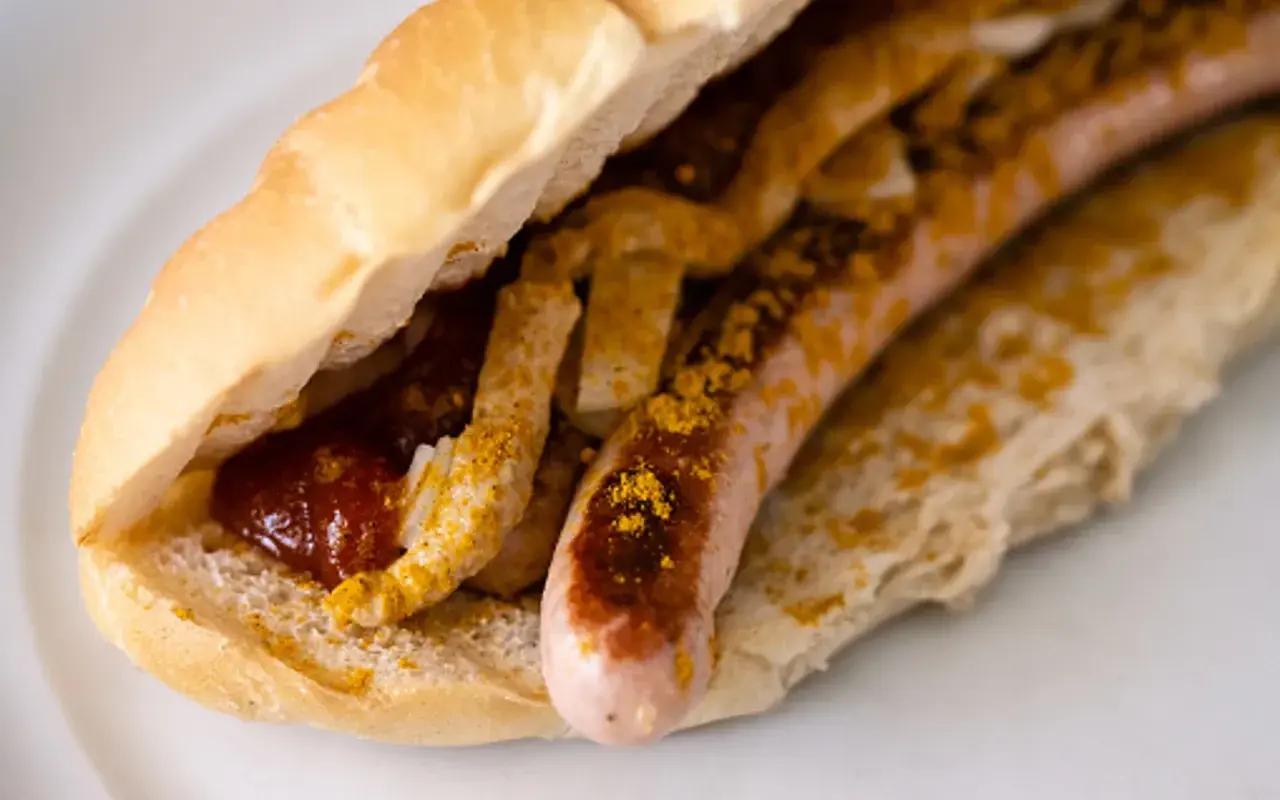Ein Brötchen mit Wurst, Ketchup und Currypulver, wie bei einem bosna rezept.