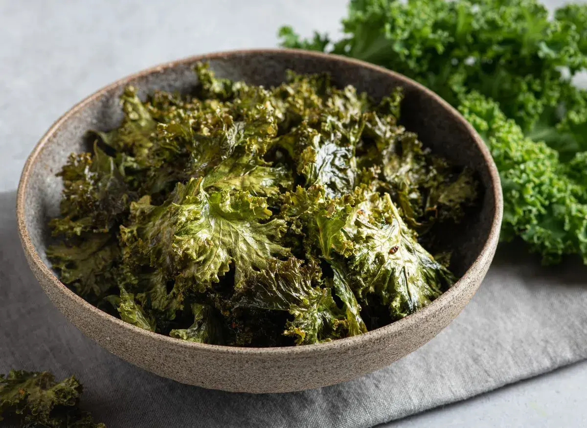 Crujientes chips de kale horneados en un tazón, perfectos para tus recetas con kale.