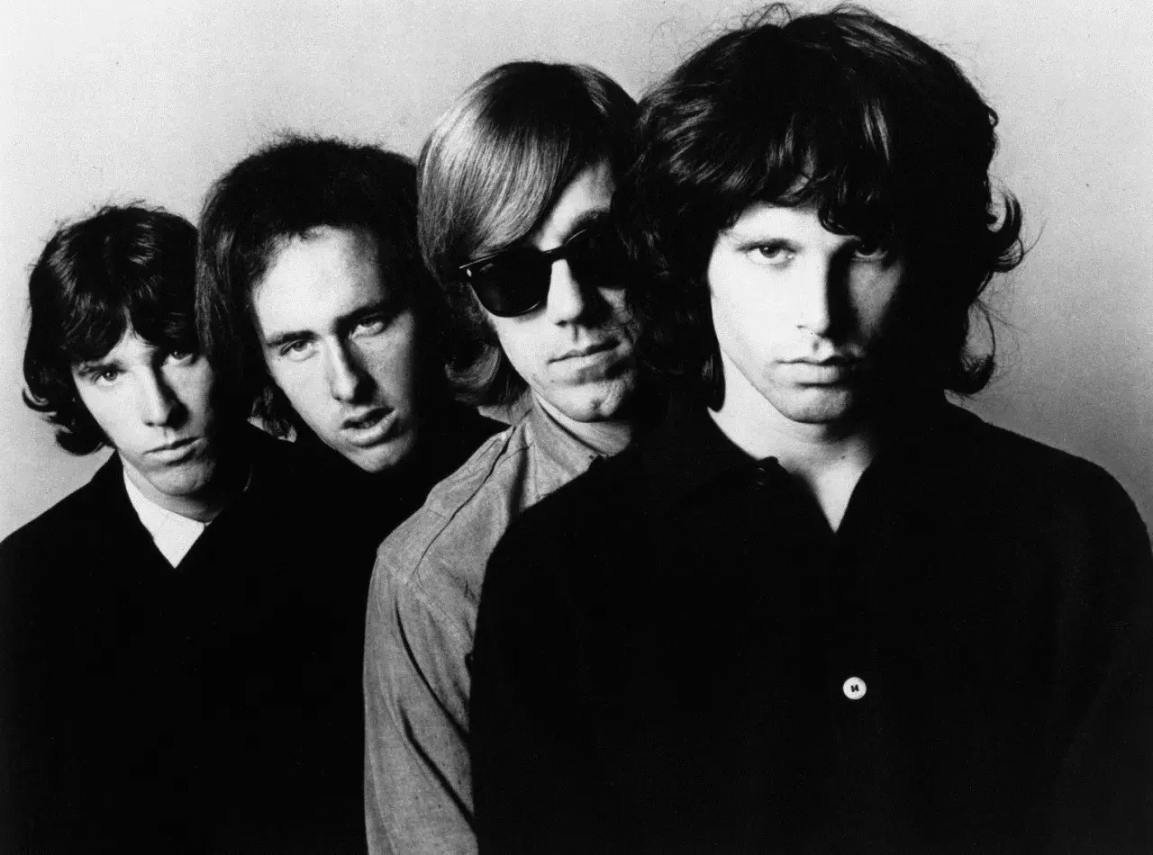 Czterech członków zespołu The Doors, w tym Jim Morrison z przodu, patrzą w obiektyw.