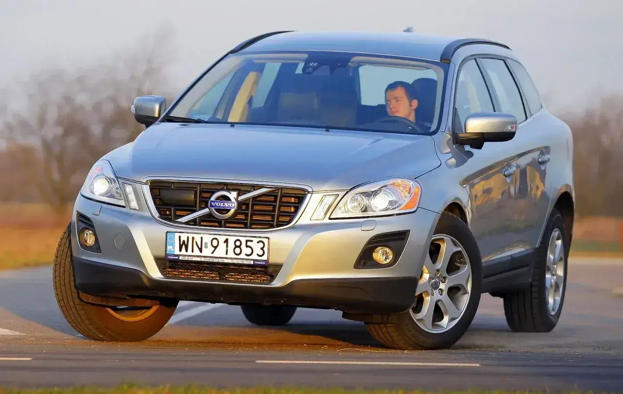 Srebrny Volvo XC60 z kierowcą na drodze. Sprawdź aktualną volvo xc60 cena i oferty.