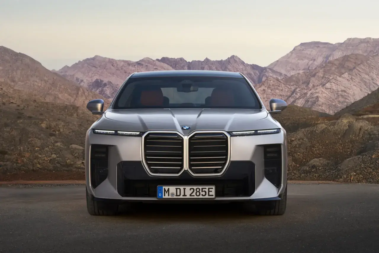 Nowe BMW Serii 7, z imponującym grillem i nowoczesnymi światłami, prezentuje się na tle górskich krajobrazów. Sprawdź jego BMW 7 cenę.