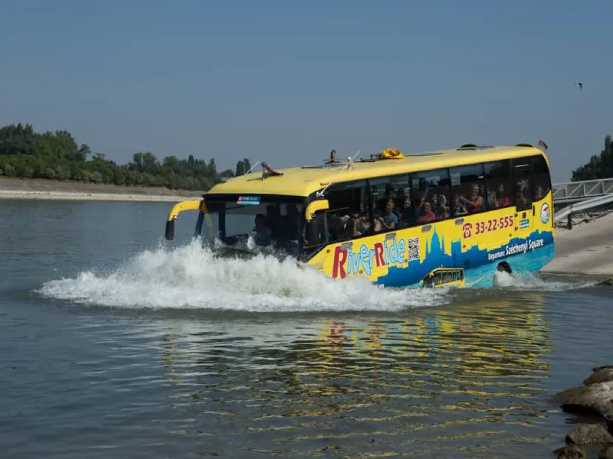 Żółty autobus do Budapesztu, River Ride, wjeżdża do wody, tworząc fale.