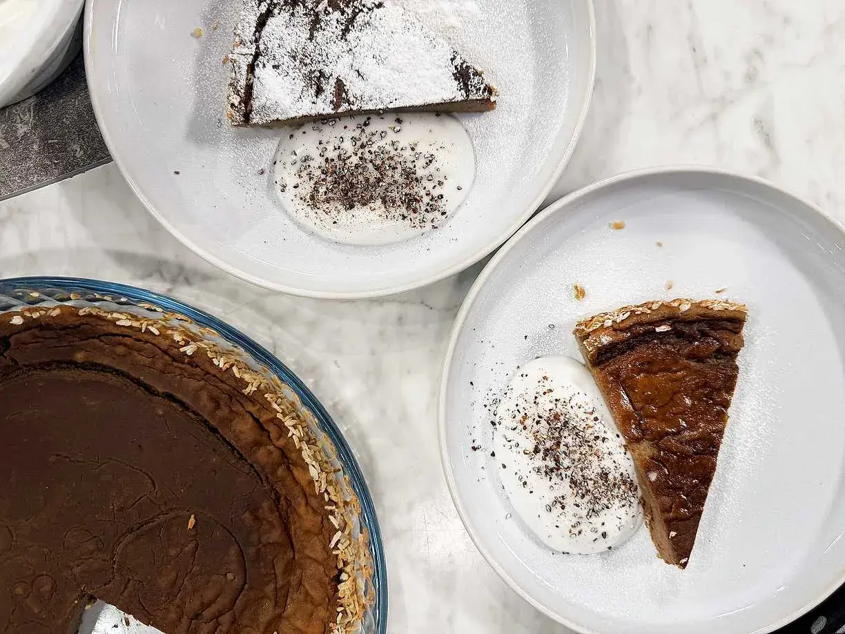 Två tallrikar med glutenfria havrekakor med kardemumma och grädde. En hel kaka i en glasform.