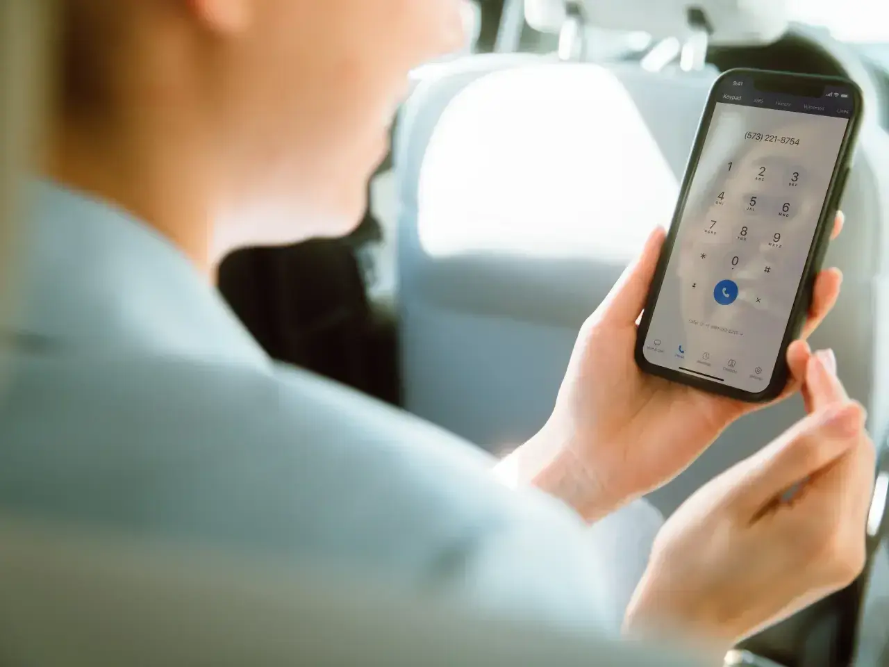 Osoba w samochodzie wybiera numer na telefonie, pokazując, jak działa voip.