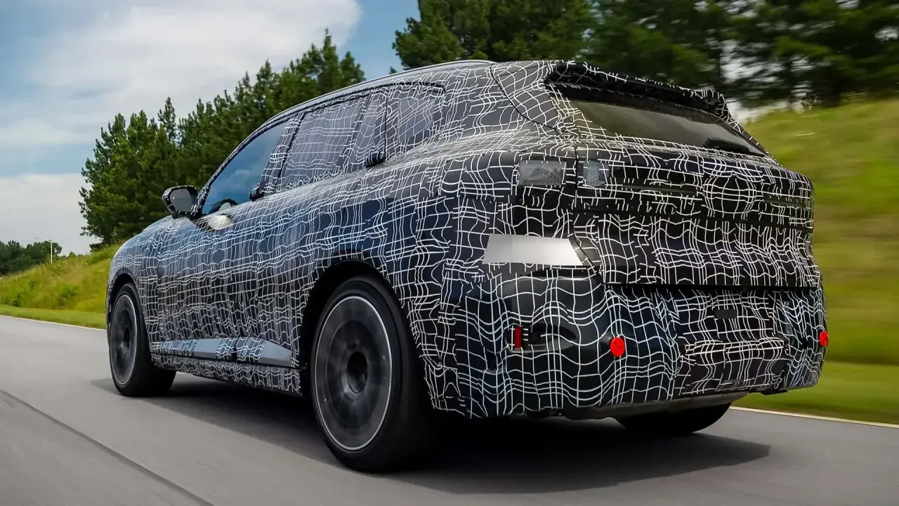 La nuova BMW X5 2026, con la sua mimetica di test, sfreccia su una strada panoramica, anticipando il futuro del design.