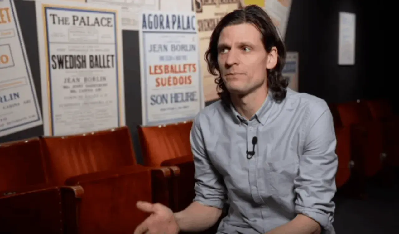 Erik Mattsson vid Dansmuseet, omgiven av affischer för Swedish Ballet och Les Ballets Suédois.