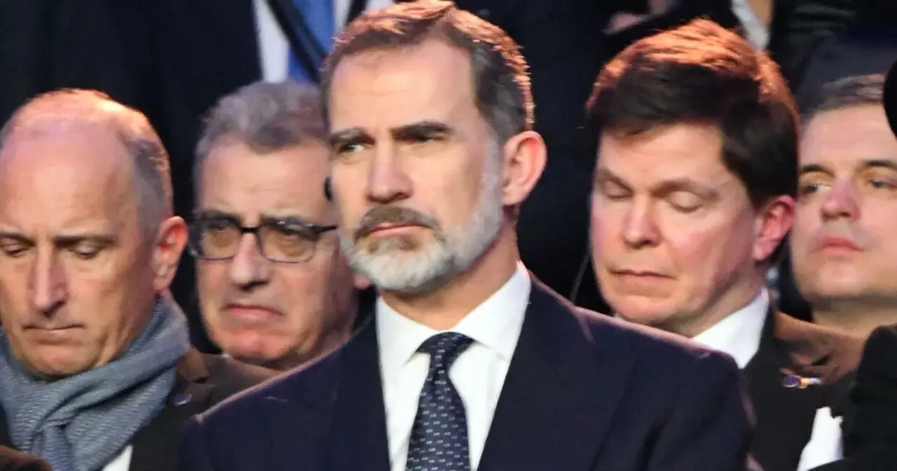 Król Hiszpanii Felipe VI w garniturze i krawacie, otoczony przez innych mężczyzn.