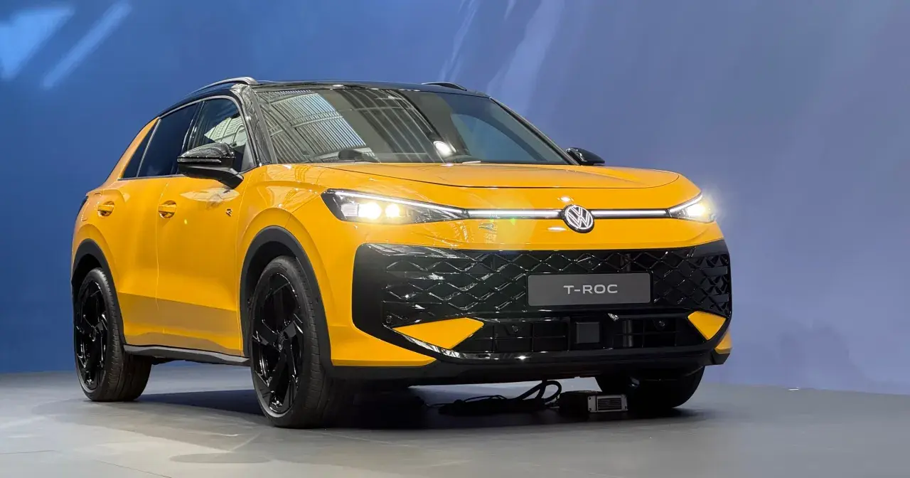 Żółty Volkswagen T-Roc z czarnym dachem i felgami. Zbliżenie na przód auta, widoczne światła LED i atrapa chłodnicy.