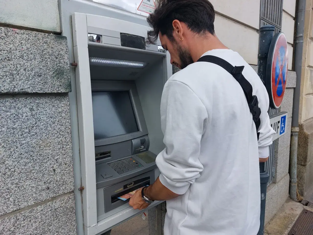 Un homme retire de l'argent à un distributeur automatique. Il suit les étapes pour comment retirer de l'argent.