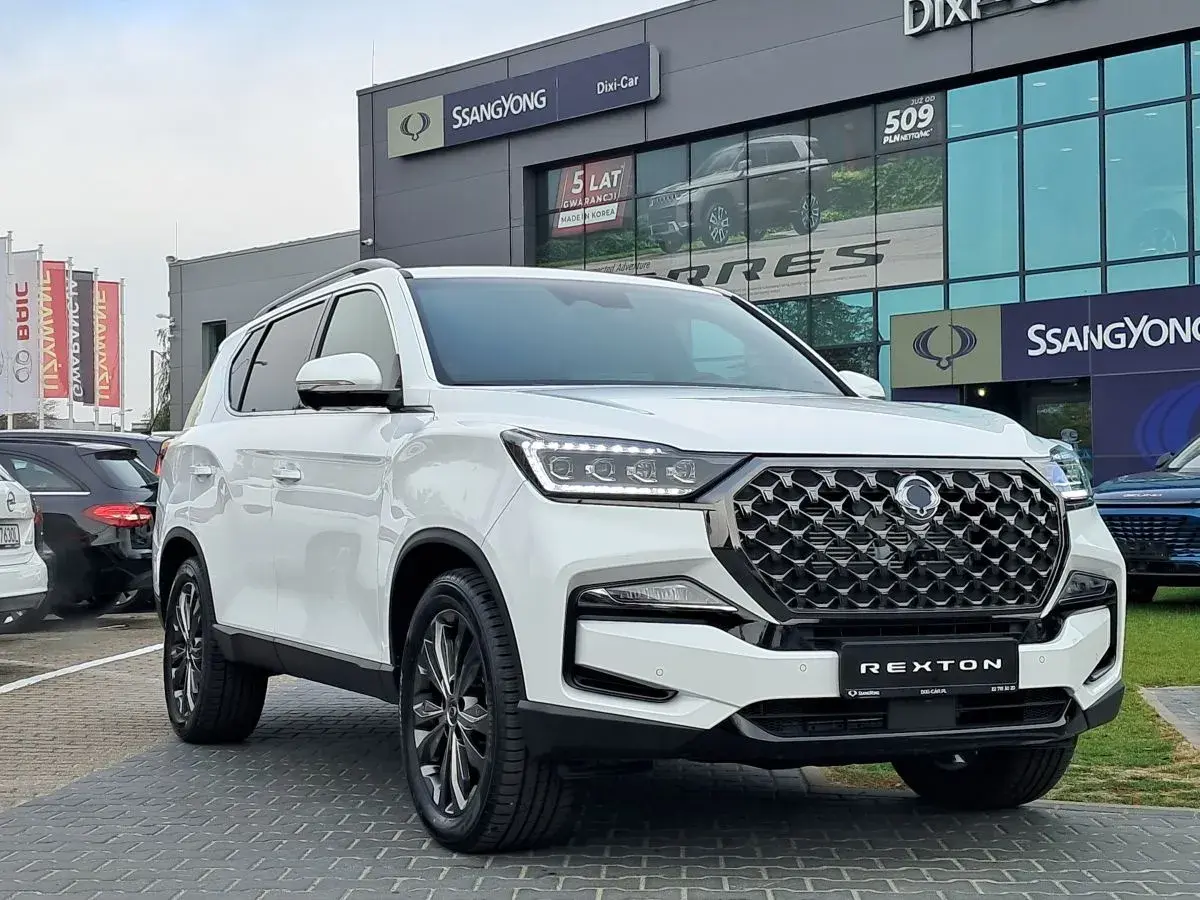 Biały SsangYong Rexton na tle salonu samochodowego. Elegancki SUV gotowy na przygodę.