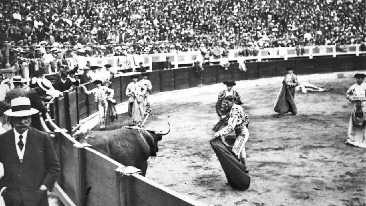En la plaza, un toro bravo se prepara para la cornada. Joselito el gallo, con su traje de luces, se enfrenta al animal ante una multitud expectante.