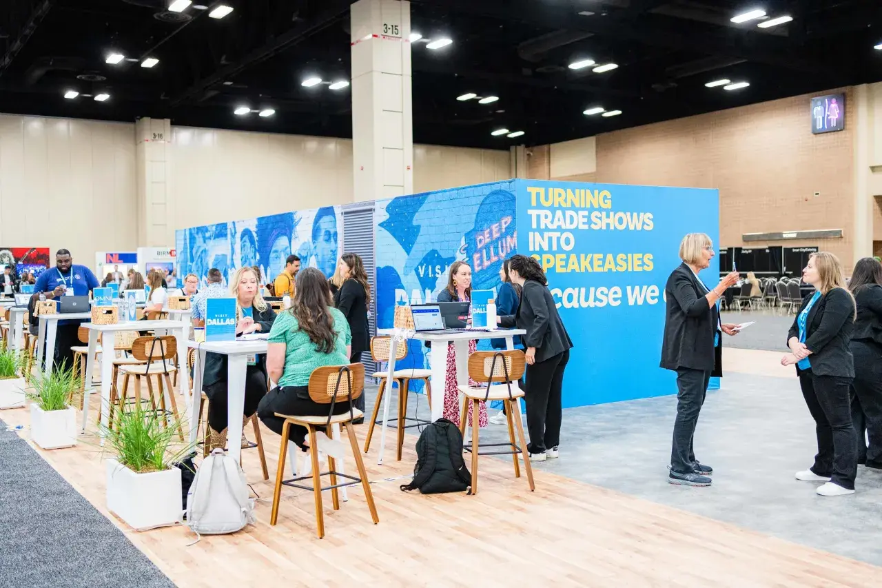 Attendees network at government trade shows, with a vibrant blue booth promoting "Turning Trade Shows Into Speakeasies.