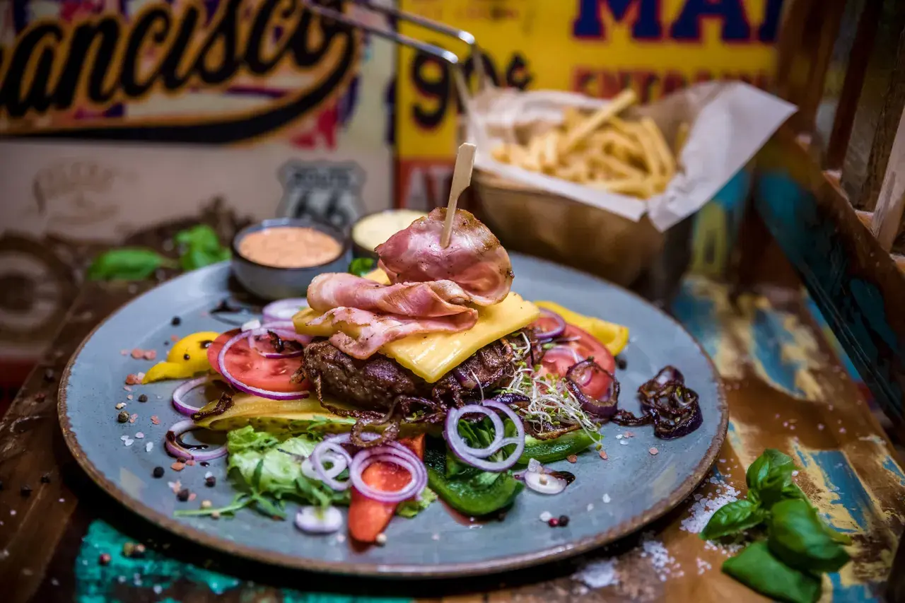 Pyszny burger z bekonem, serem i warzywami. Prawdziwe niebo w gębie w Karpaczu! Do tego frytki i sosy.