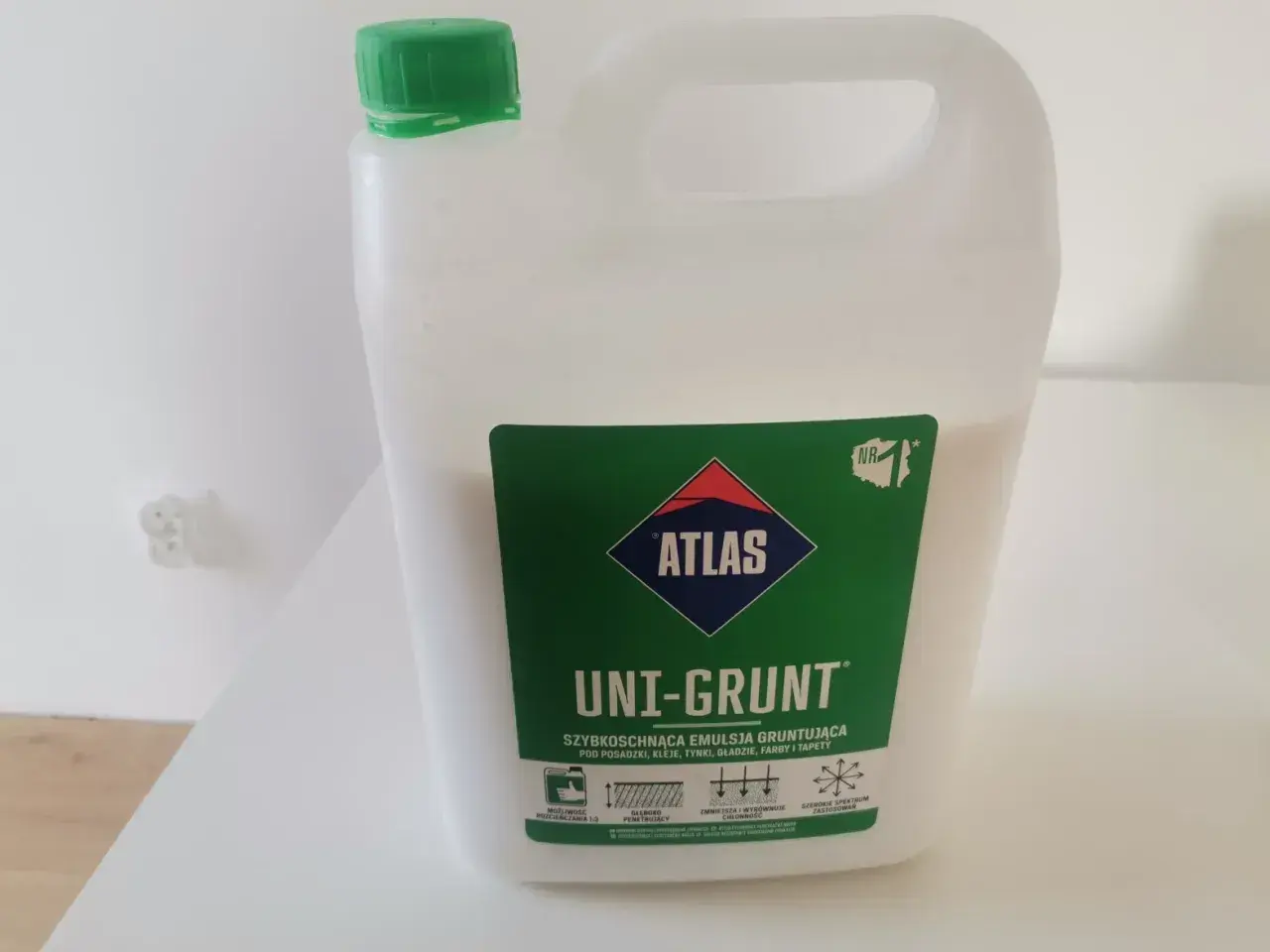 Biały kanister z zieloną nakrętką zawiera emulsję gruntującą Atlas Uni-Grunt. Idealny do przygotowania podłoża pod tynki i farby.