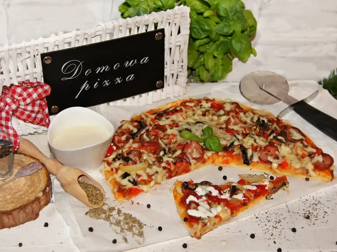Domowa pizza bez drożdży, z kiełbasą i warzywami, gotowa do podania. Obok sos i przyprawy.