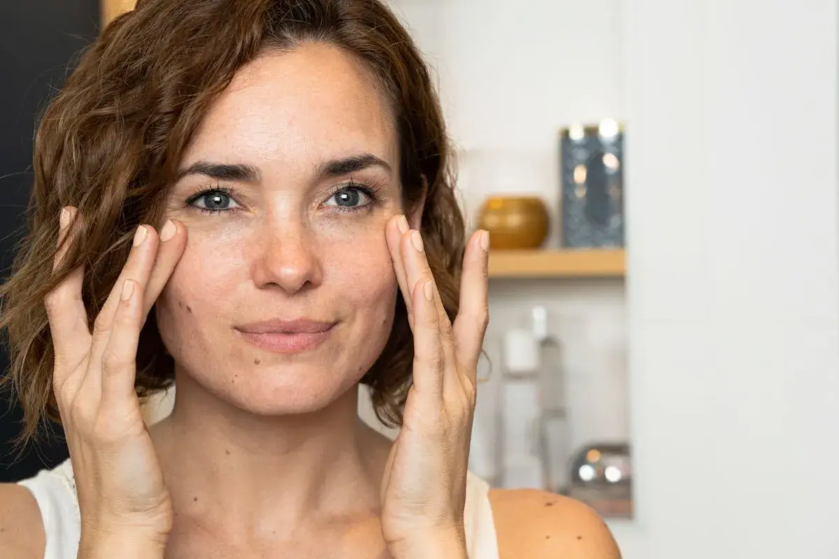 Une femme applique une crème sur son visage, découvrant les premières rides.