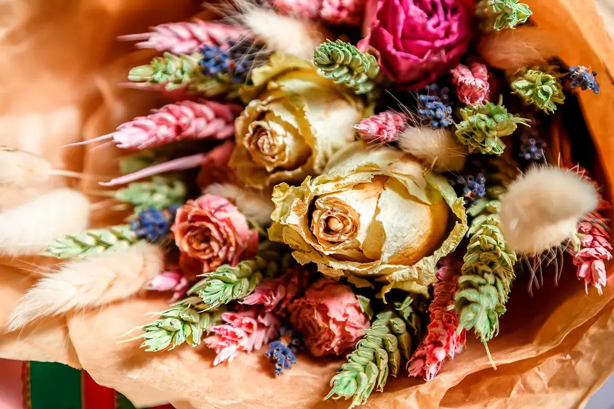 Vacker bukett med torkade rosor, lavendel och andra torkade blommor i varma färger.