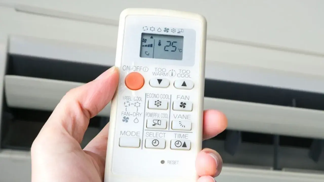 Mano sujetando control remoto de aire acondicionado. El símbolo del triángulo indica la función de enfriamiento.