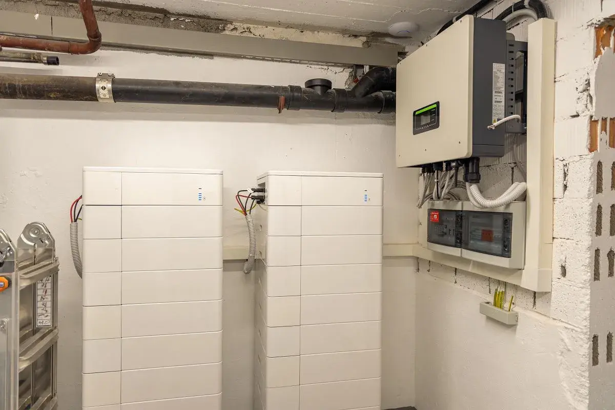 Dwa białe, modułowe systemy **bess** obok siebie, podłączone do falownika i rozdzielnicy elektrycznej.