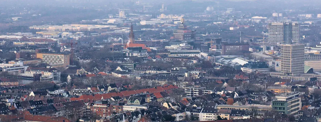 Rozległy krajobraz miejski, gdzie widać charakterystyczne budynki i dachy, tworzy obraz miasta Dortmund.
