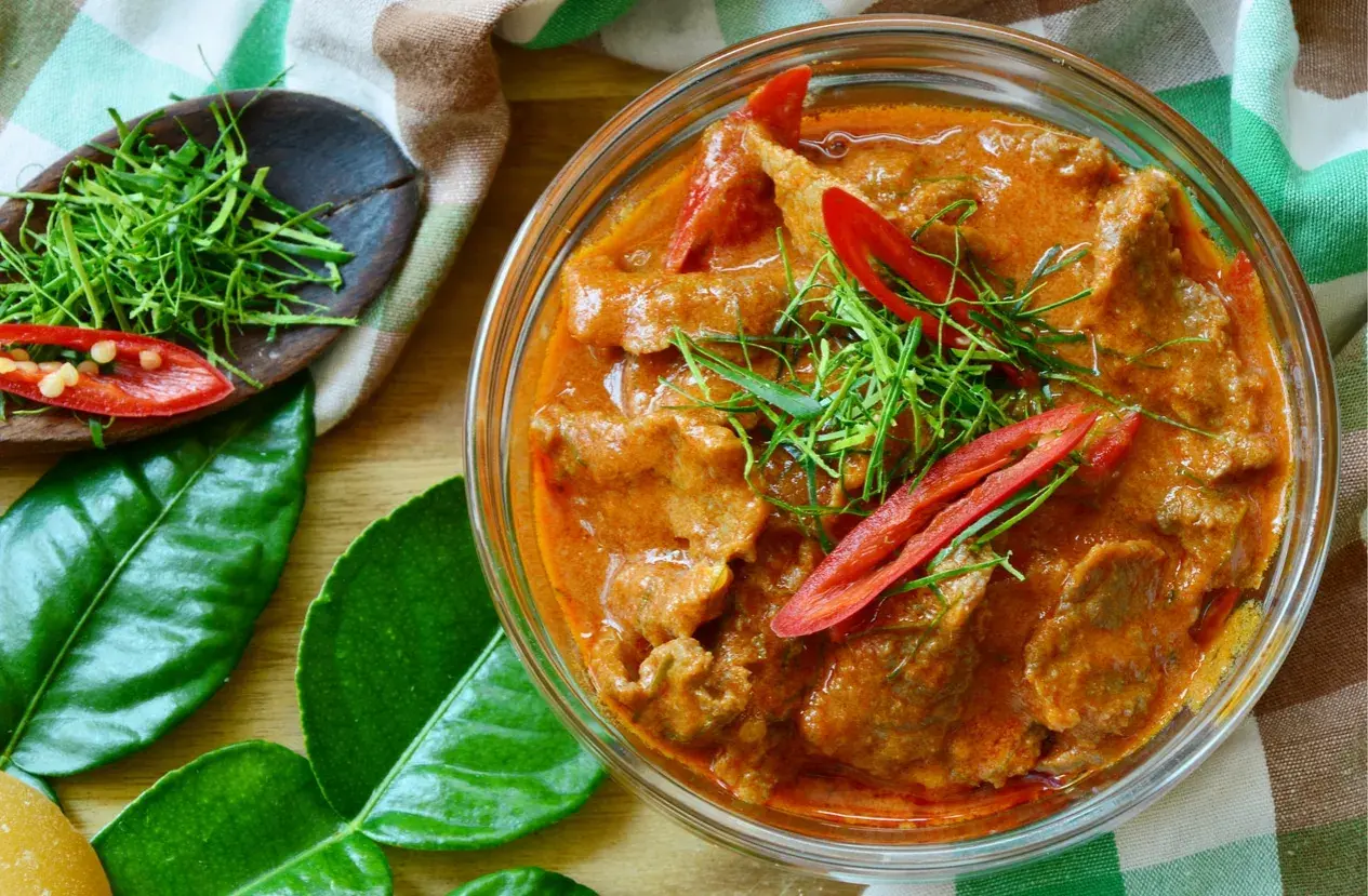 Un délicieux boeuf curry rouge, garni de piments et d'herbes fraîches, prêt à être dégusté.