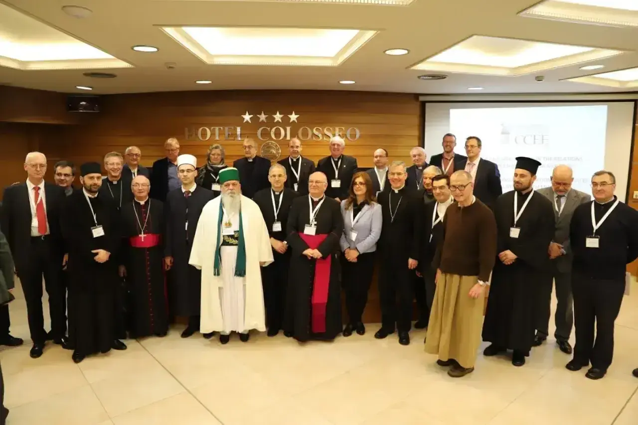 Grupa duchownych i świeckich, w tym muzułmanin w białej szacie, dyskutuje o albania religia.