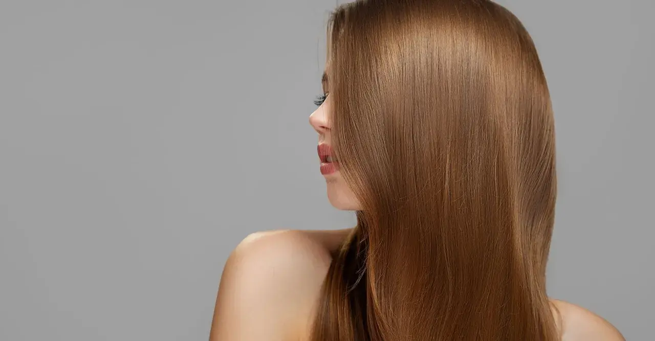 Mujer con cabello largo y liso de tono castaño claro, con reflejos dorados.
