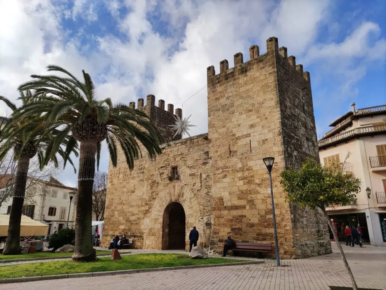 Puerta de Alcudia, Valencia, con palmeras y cielo azul.
