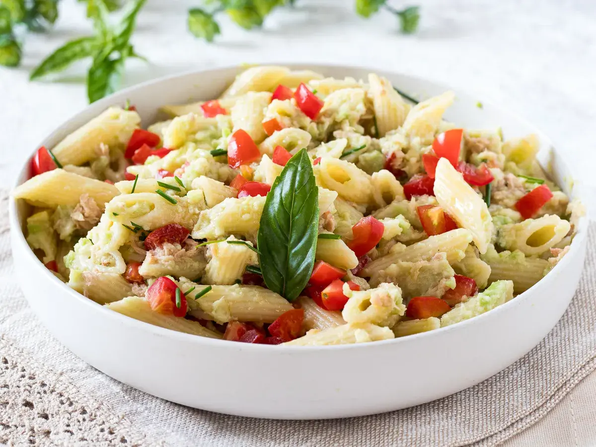 Penne con tonno e avocado, un piatto fresco e colorato con pomodorini e basilico.