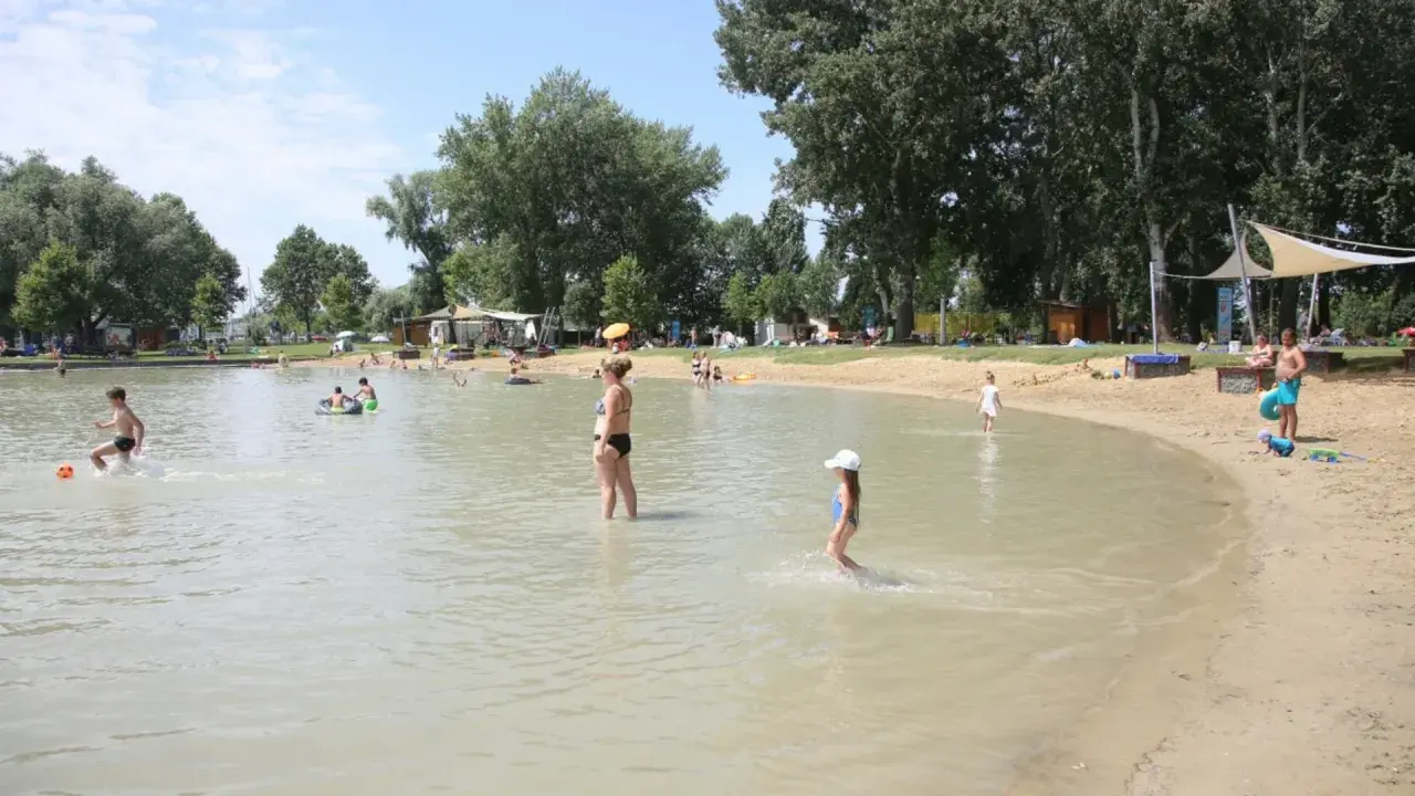 Ludzie kąpią się i bawią na piaszczystej plaży nad jeziorem. Gdzie jest Balaton? Węgry, Szigliget.